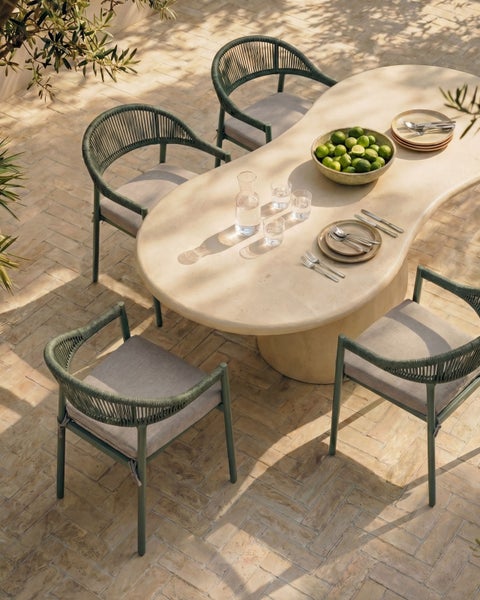 Modernes Gartenmöbel-Set mit einem ovalen Esstisch in Steinoptik und vier grünen Gartenstühlen mit Seilgeflecht und grauen Kissen auf einer Terrasse.