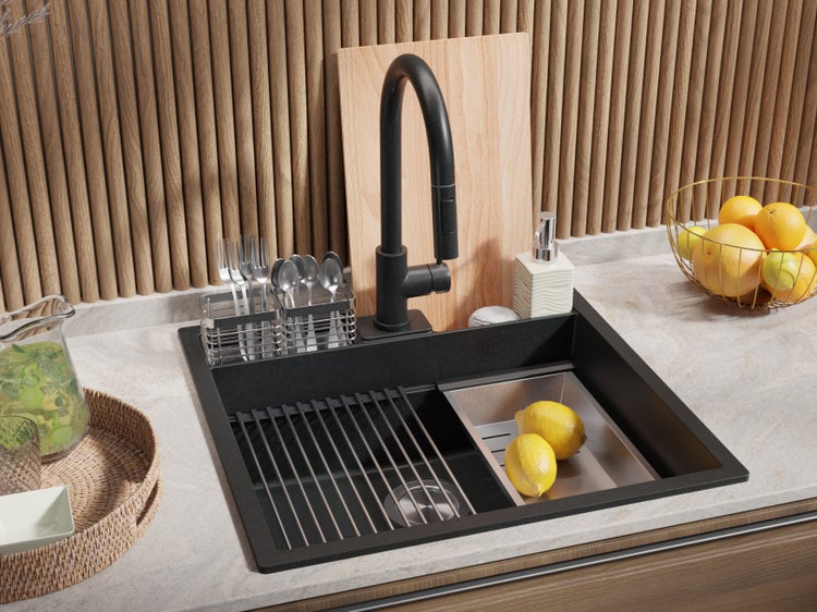 Spüle mit Abtropfgestell, Armatur, Spülmittelspender, Schneidebrett und Geschirrkorb auf einer Küchentheke mit Obstschale.