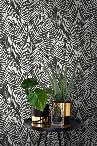 Dekorative Tapete mit Palmenmuster und Zimmerpflanzen auf einem Tisch.