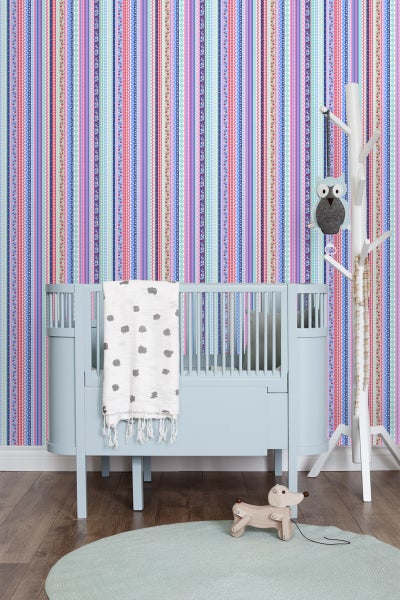 Babyzimmer mit Kinderbett, Teppich, Spielzeug und gestreifter Tapete