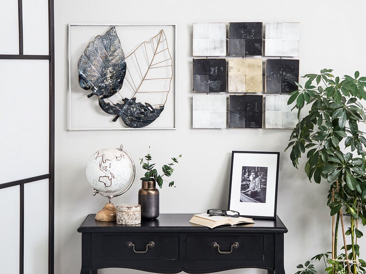 Dekoratives Wohnambiente mit Wanddeko, Globus und Zimmerpflanze auf einer Kommode.