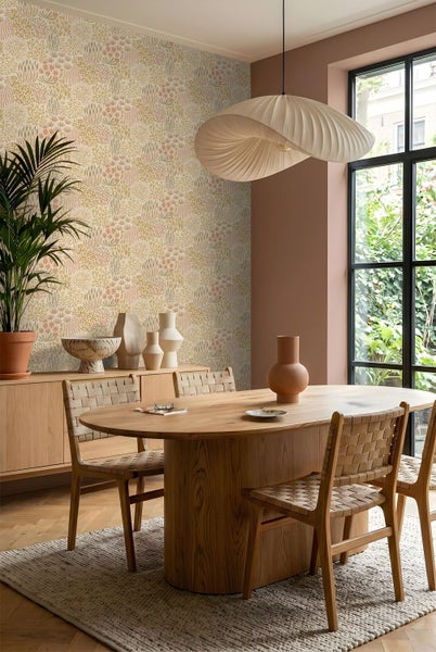 Vliestapete mit floralem Muster in einem hellen Esszimmer mit Holztisch, gewebten Stühlen und moderner Pendelleuchte.