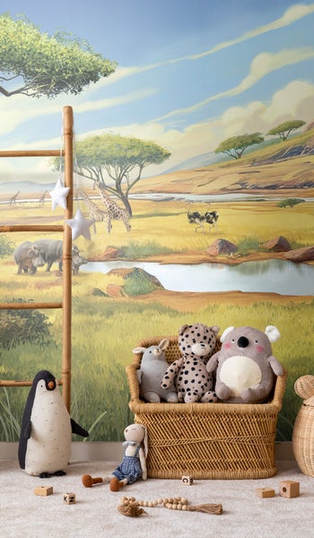 Kinderzimmer mit Safari-Tapete, Korbsessel und Stofftieren.