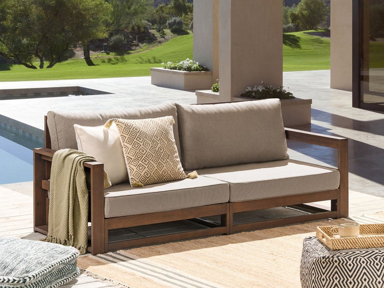 Zweisitzer-Gartensofa mit Kissen und Decke auf einer Terrasse mit Pool