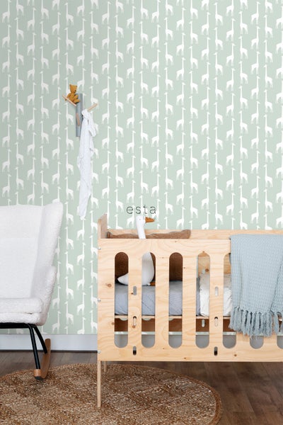 Kinderzimmer mit Gitterbett, Schaukelstuhl und Tapete mit Giraffenmuster.