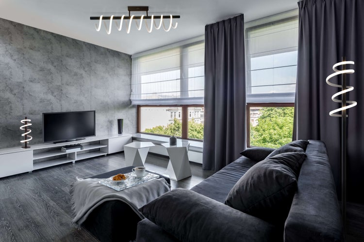 Wohnzimmer mit Sofa, Fernseher und Beleuchtung