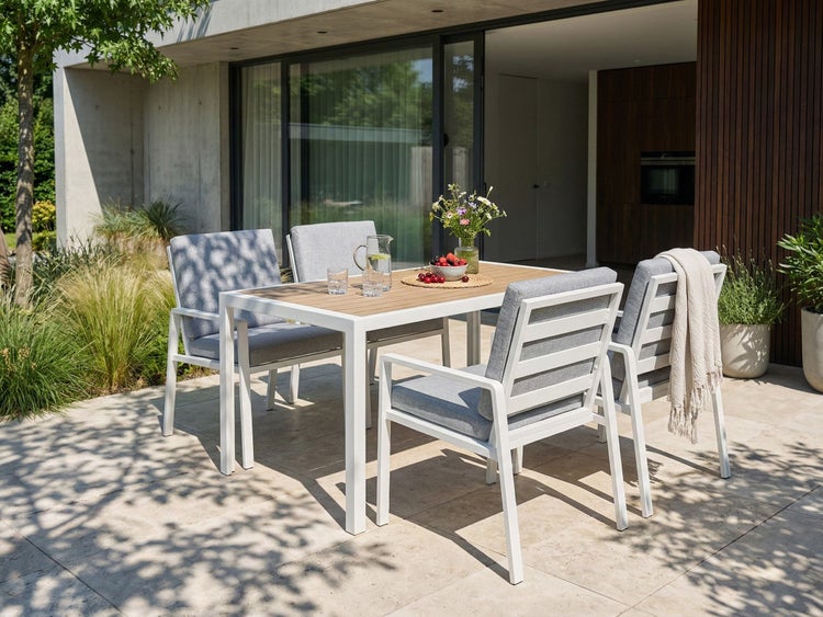 Gartentisch mit vier Stühlen auf einer Terrasse mit Geschirr und Blumenvase
