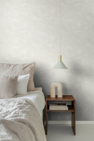 Schlafzimmer mit Bett, Nachttisch und Pendelleuchte vor einer strukturierten Wandtapete