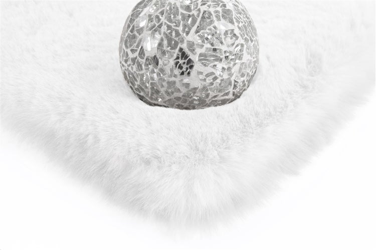 Nahaufnahme eines weißen, flauschigen Kunstfells mit einer dekorativen Mosaikkugel.