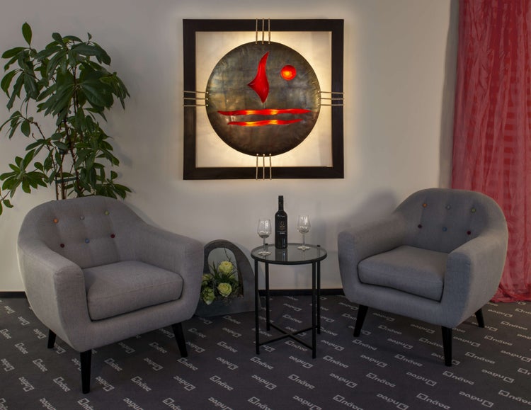 Wohnzimmer mit zwei Sesseln, kleinem Tisch mit Wein und Gläsern, Dekoration und beleuchtetem Wandbild