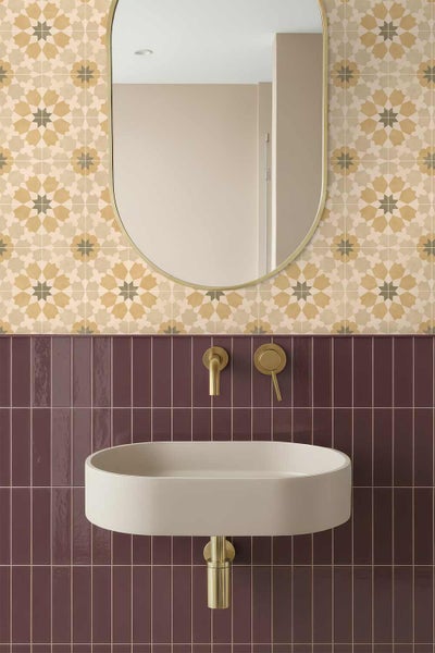 Modernes Badezimmer mit ovalem Aufsatzwaschbecken, goldener Wandarmatur, ovalem Spiegel und zweigeteilter Wandgestaltung mit Ziermustern.