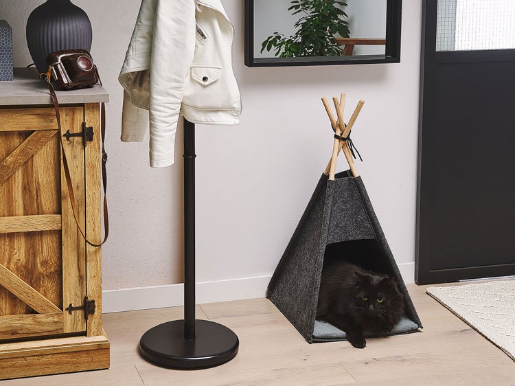 Katzenzelt Tipi aus grauem Filz mit Holzstäben auf einem Holzfußboden in einem modern eingerichteten Flur mit einer schwarzen Katze.
