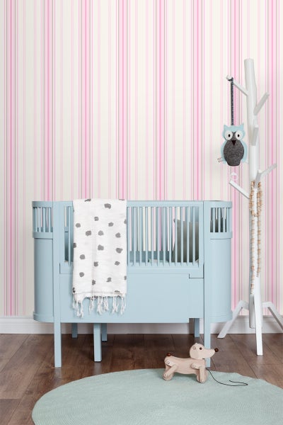 Kinderzimmer mit Gitterbett, Spielzeug und gestreifter Tapete