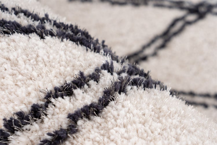 Nahaufnahme eines Hochflor-Teppichs mit Linienmuster und weicher Textur.