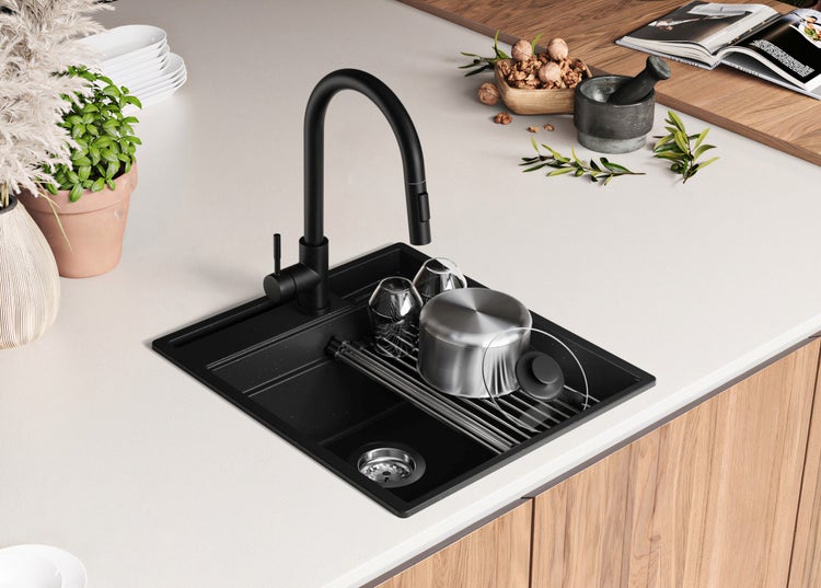 Schwarze Küchenspüle mit Armatur auf einer Küchentheke mit Geschirr