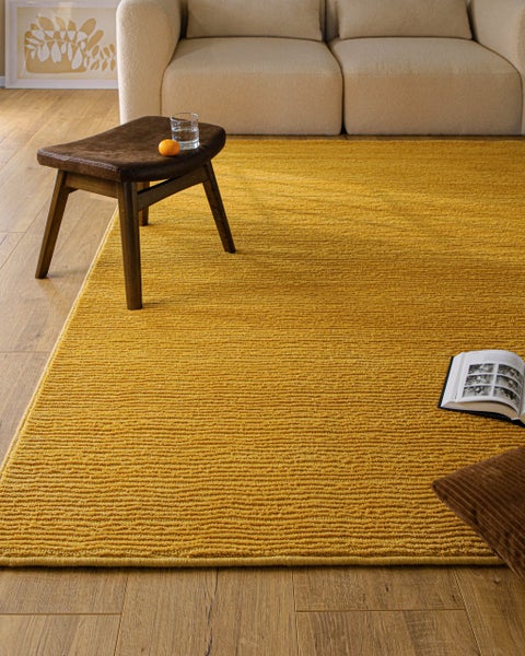 Gelber strukturierter Teppich mit Rippenmuster in einem hellen, modernen Wohnzimmer auf Holzboden.