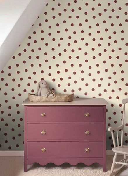 Vliestapete mit Punktemuster in einem Kinderzimmer an einer Wand hinter einer Kommode mit einem Stofftier.