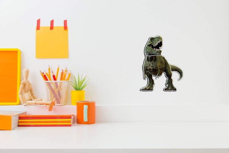 Wandtattoo Tyrannosaurus Rex an einer weißen Wand über einem Schreibtisch mit Schreibutensilien und einer Pflanze.