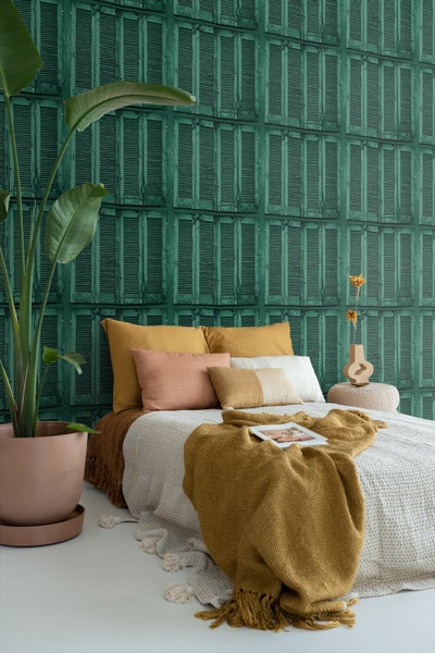 Schlafzimmer mit Bett, Kissen, Decken und einer Wand mit Fensterladen-Tapete