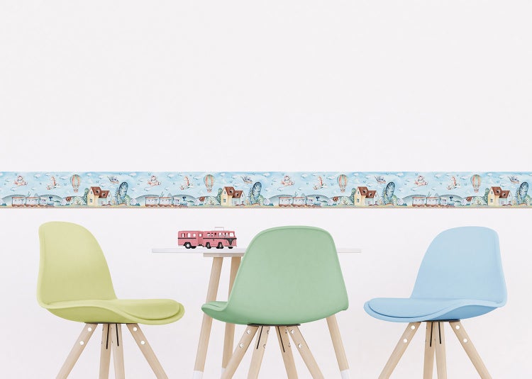 Selbstklebende Kinderzimmer-Bordüre mit Motiven von Zügen, Häusern und Heißluftballons über einem Kindertisch mit Stühlen.