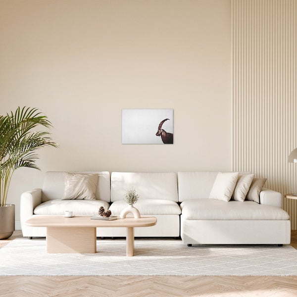 Wohnzimmer mit Ecksofa, Tisch und Wandbild eines Steinbocks.