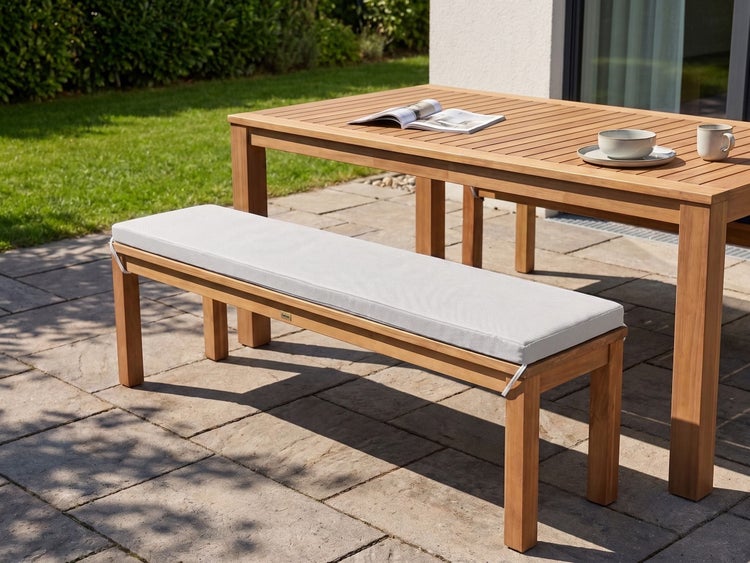 Gartenbank aus Holz mit einem bequemen Sitzkissen auf einer Terrasse stehend vor einem passenden Holztisch