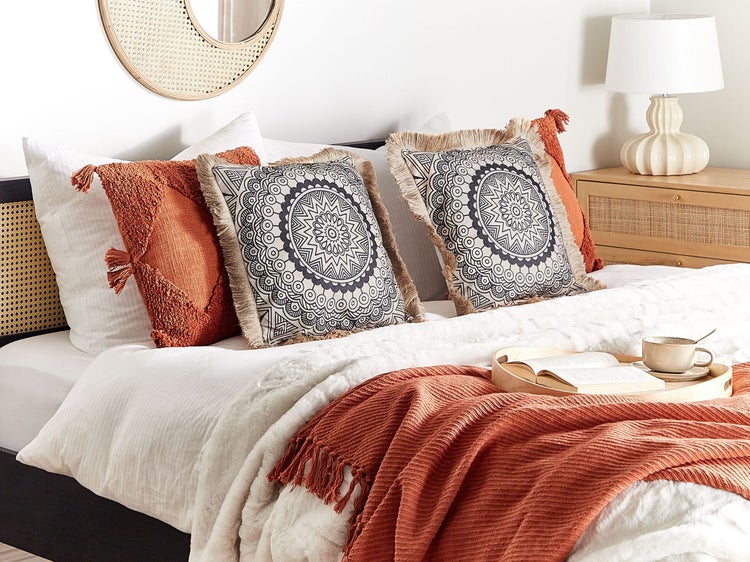 Dekoratives Schlafzimmer mit Kissen, Decke, Nachttischlampe und Lesetablett