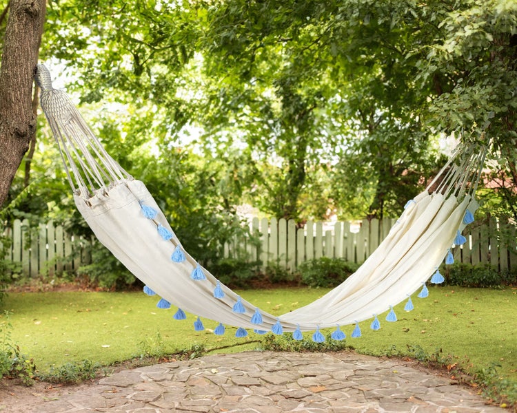 Hängematte mit Baumwollstoff und dekorativen Quasten im Garten