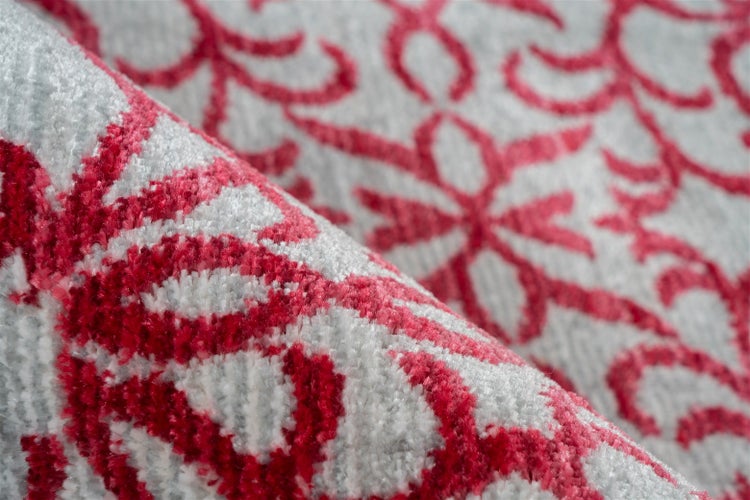 Nahaufnahme eines Teppichs mit rosafarbenem Ornamentmuster und weicher, flauschiger Textur.