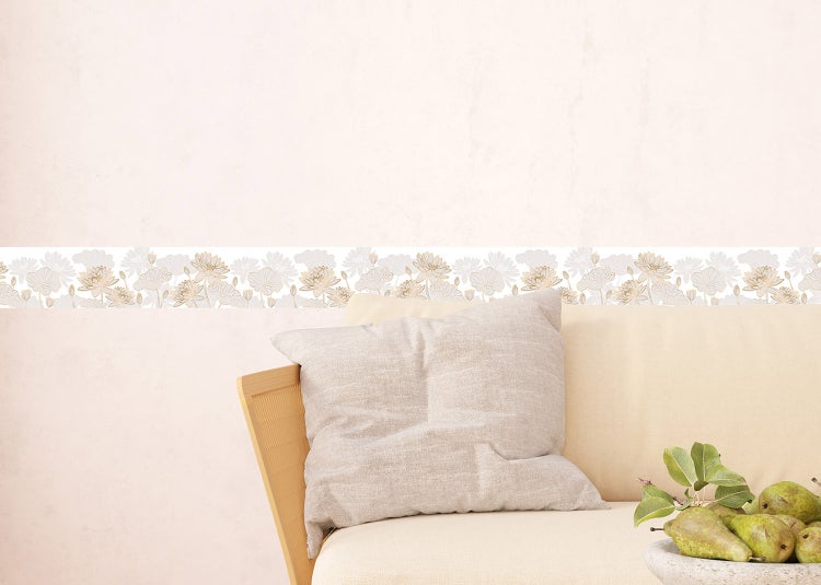 Tapetenbordüre mit floralem Lotusmuster in einem hellen Wohnzimmer hinter einem Sofa mit Kissen.