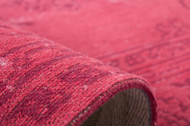 Detailaufnahme eines gewebten roten Teppichs mit sichtbarer Oberflächenstruktur und umgeschlagener Kante.