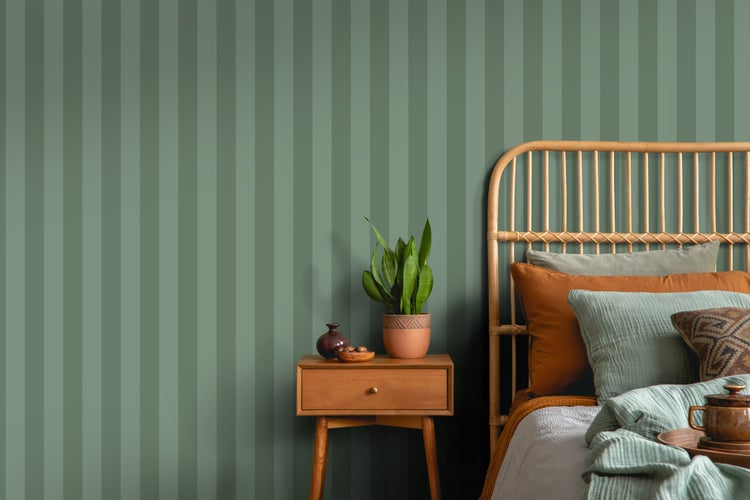 Schlafzimmer mit Rattanbett, Nachttisch und gestreifter Tapete