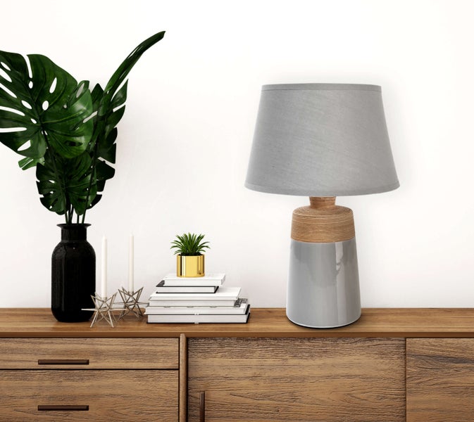 Dekorative Szene auf einem Holzschrank mit einer Tischlampe, einer Pflanze, Büchern und Kerzen