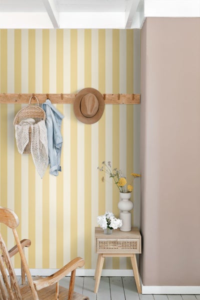 Heller Raum mit vertikal gestreifter Vliestapete, hölzerner Wandgarderobe, Nachttisch und einem Holzstuhl.