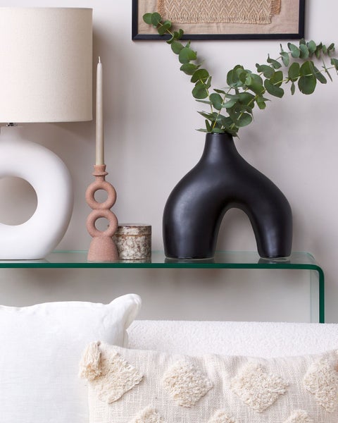 Dekoratives Stillleben mit Lampe, Kerzenständer, Dose und Vase auf einem Regal