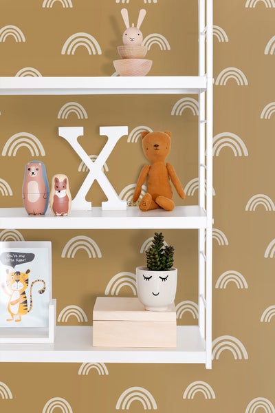 Regal mit Dekorationsobjekten im Kinderzimmer vor einer Tapete mit Regenbogenmuster