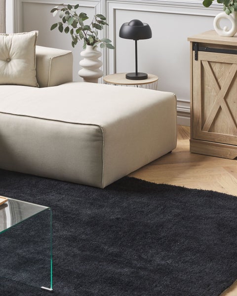 Wohnzimmer-Szene mit Sofa, Teppich, Tischlampe und Holzschrank