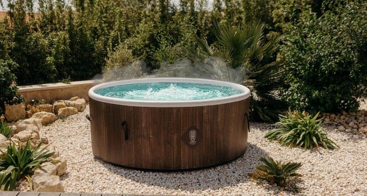 Aufblasbarer Whirlpool in Holzoptik im Garten auf Kies mit Bepflanzung.