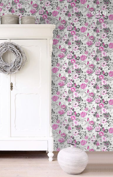 Szene mit floral gemusterter Tapete, weißem Schrank und Dekorationen für ein helles, organisiertes Ambiente.