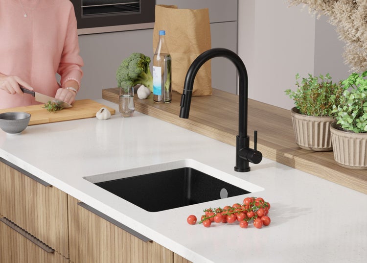 Küchenszene mit schwarzer Spüle, Armatur und Person beim Kochen