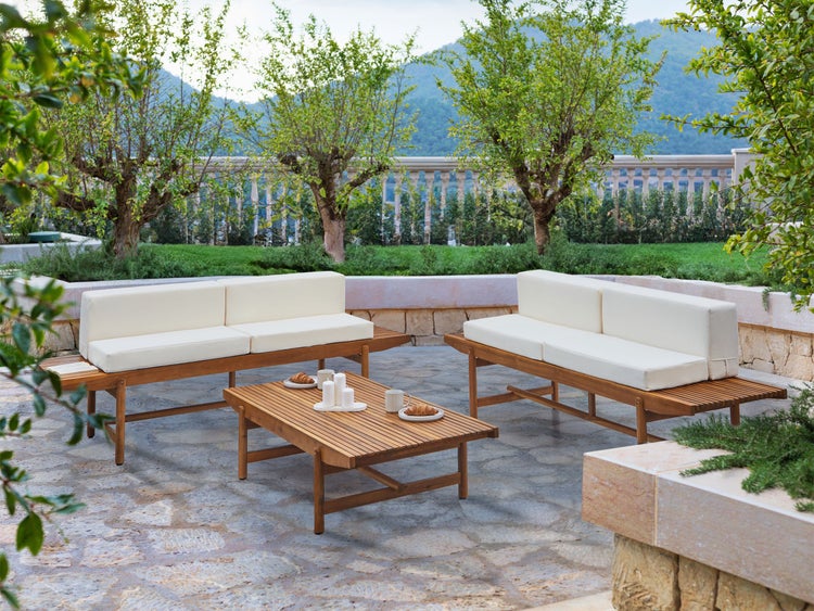 Gartenszene mit zwei Bänken mit Auflagen und einem Couchtisch auf einer Terrasse