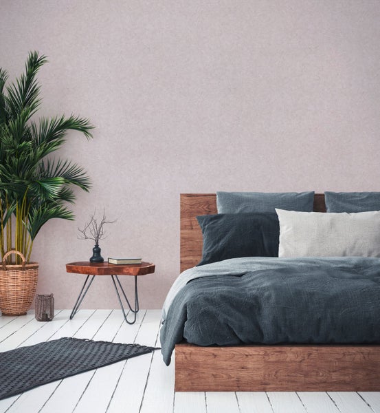 Schlafzimmer mit Bett, Beistelltisch, Zimmerpflanze und Tapetenmuster