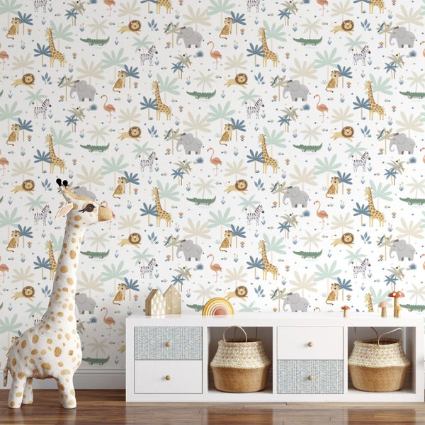 Vliestapete mit Safarimotiven in einem hellen Kinderzimmer mit weißem Sideboard und großem Giraffen-Stofftier.
