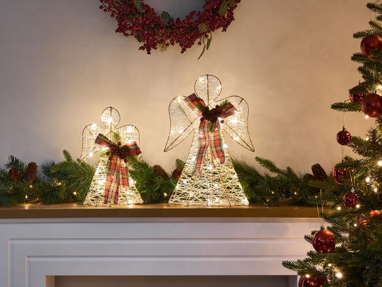 Dekoratives Arrangement mit zwei Engel Figuren, Weihnachtskranz und dekoriertem Weihnachtsbaum.