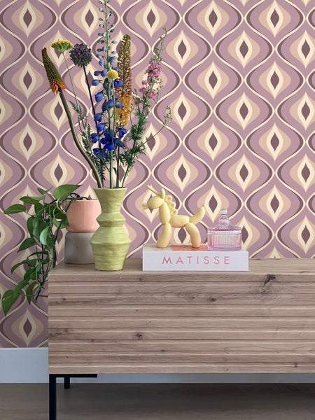 Dekoratives Interieur mit gemusterten Tapeten, Holzkommode und Blumen