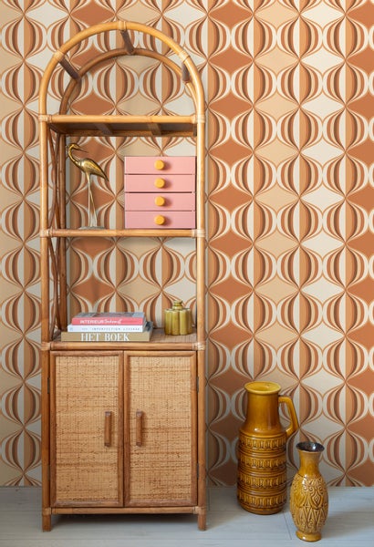 Dekoratives Regal aus Rattan mit Deko-Elementen vor gemusterter Tapete
