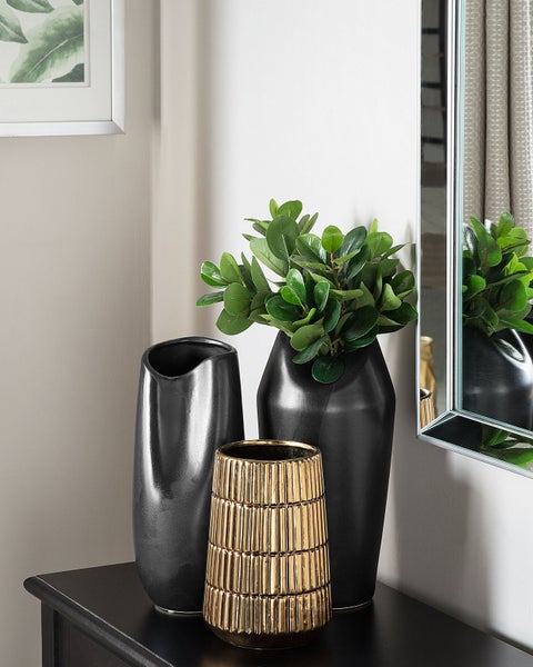 Dekoratives Stillleben mit schwarzen und goldfarbenen Vasen auf einem Tisch