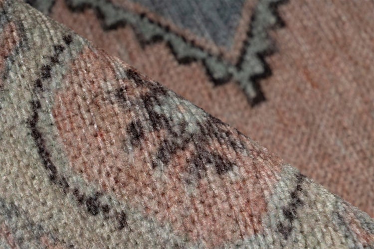 Nahaufnahme eines gewebten Teppichs mit geometrischem Muster und sichtbarer Textur.