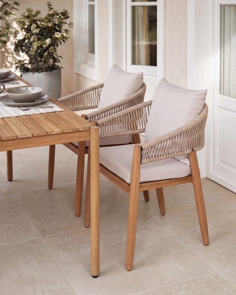 Gartenstühle aus Holz mit geflochtenen Armlehnen und Sitzpolstern an einem Holztisch auf einer Terrasse