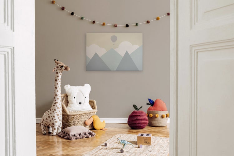 Kinderspielzimmer mit Wandbild Berglandschaft, Giraffe Stofftier, Rattan Sessel, Kissen und Spielzeug auf Holzboden